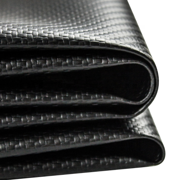 A close-up of a black carbon fiber textured material, showing a woven pattern and glossy finish, rolled over on a white background.