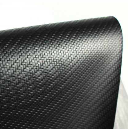 A close-up of a black carbon fiber textured material, showing a woven pattern and glossy finish, rolled over on a white background.