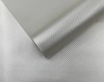 A close-up of a light gray to silver textured material, showing a diagonal fold that reveals a slightly glossy, satin-like finish.