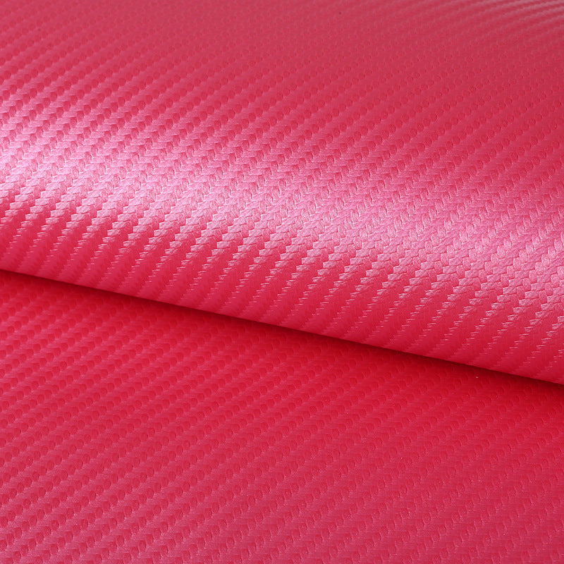 A close-up of a rolled piece of textured material with a diagonal woven pattern in bright pink and red tones.